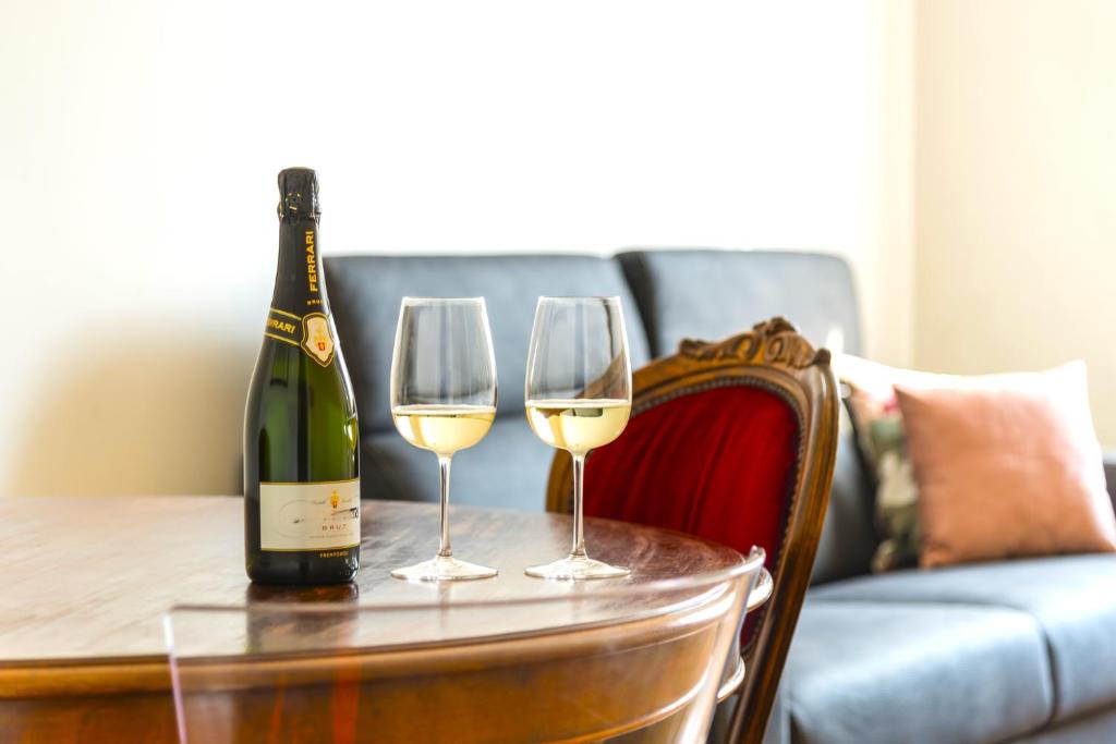 une bouteille de vin et deux verres sur une table dans l'établissement Hostly-Suite le Maioliche-Charme in Town Center, à Pise