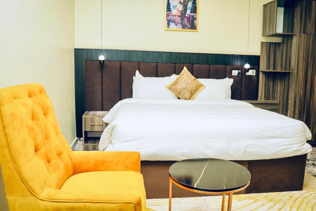 a hotel room with a bed and a chair at Grand Palmac Hotel in Abuja