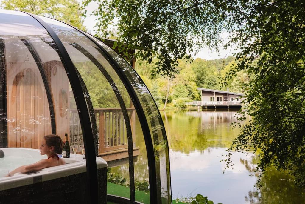 un homme dans une baignoire à côté d'une masse d'eau dans l'établissement Le chant des oiseaux - Chalet, à Saint Lo