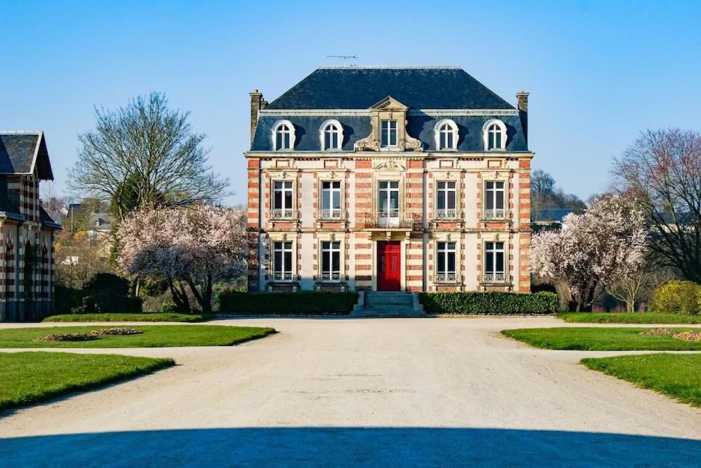 une grande maison avec une porte rouge dans une allée. dans l'établissement Le chant des oiseaux - Chalet, à Saint Lo
