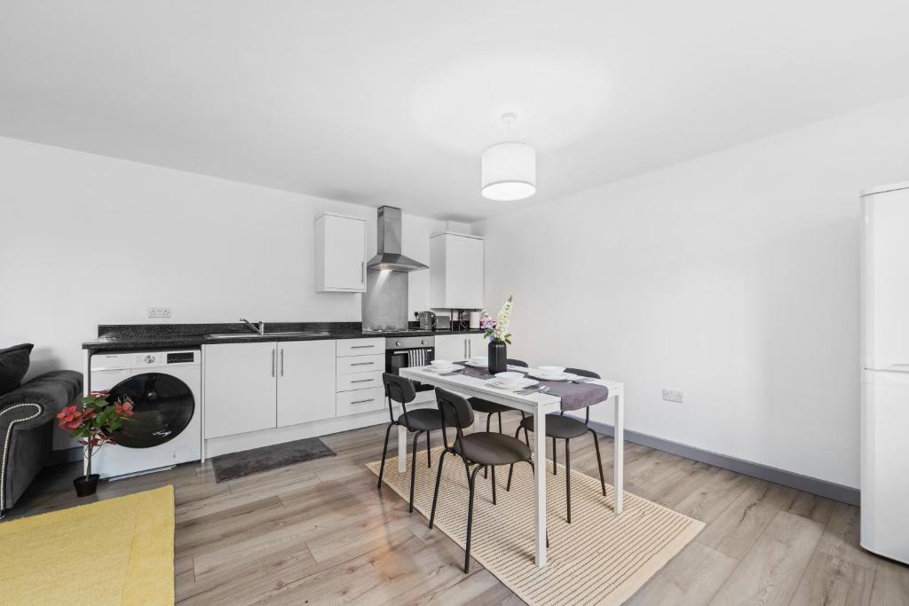 a white kitchen with a table and chairs at Budget 2-Bed House 10mins to Leeds City Centre in Leeds