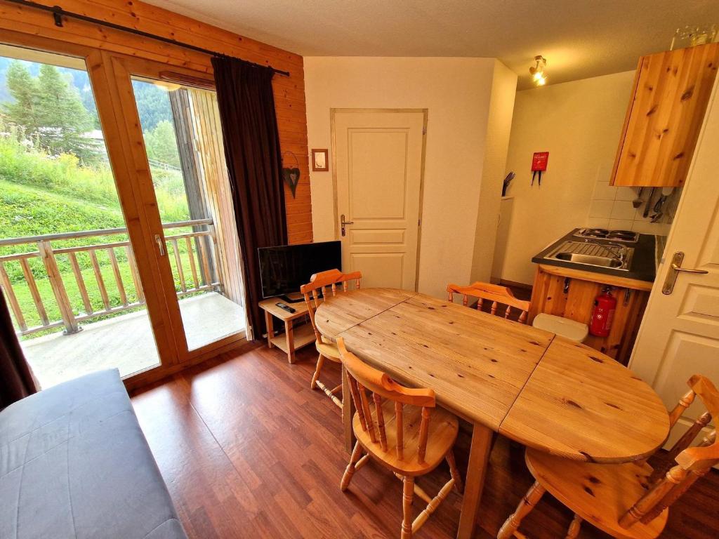 une cuisine et une salle à manger avec une table et des chaises en bois dans l'établissement Appartement 2 pièces + cabine, 6 personnes, bien situé à 30m du télécabine - Rue du Cheval Blanc, Modane - FR-1-265-187, à Valfréjus