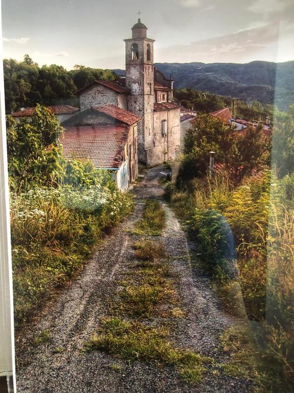 an old building with a tower on top of a dirt road at AL CASTELLO Cengio Alto in Cengio