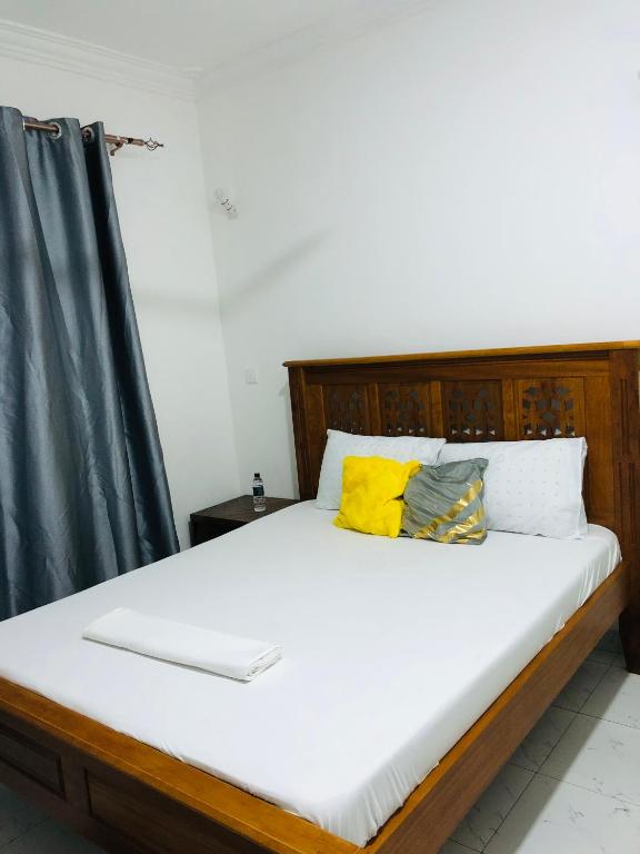 a bed with a wooden headboard and two pillows at Queens Luxury Studio Mombasa in Mombasa