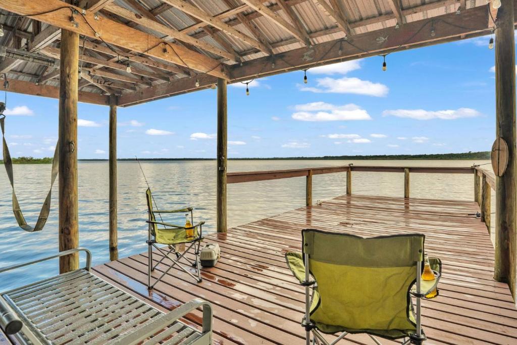 a dock with two chairs and a hammock on the water at Nature's Nest Lake House in Lake Wales