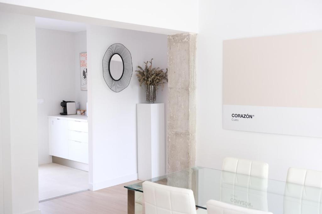 een witte eetkamer met een glazen tafel en witte stoelen bij Corazón Cuatro in Jaén