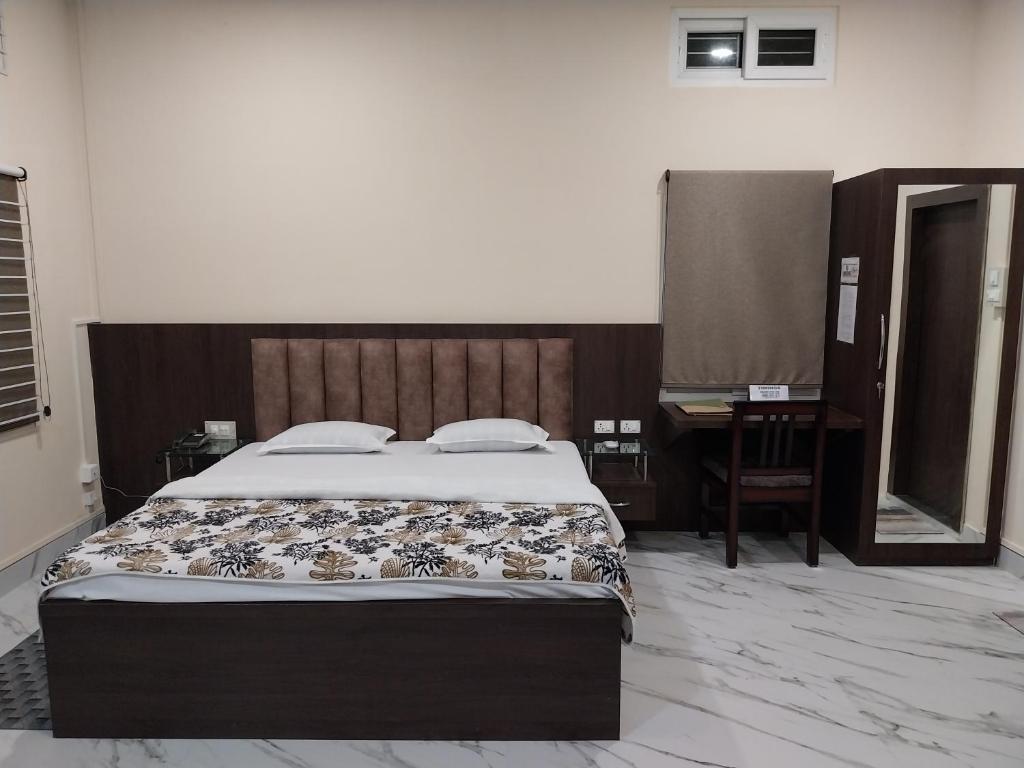 a bedroom with a bed and a desk and a mirror at Bononi in Jorhāt