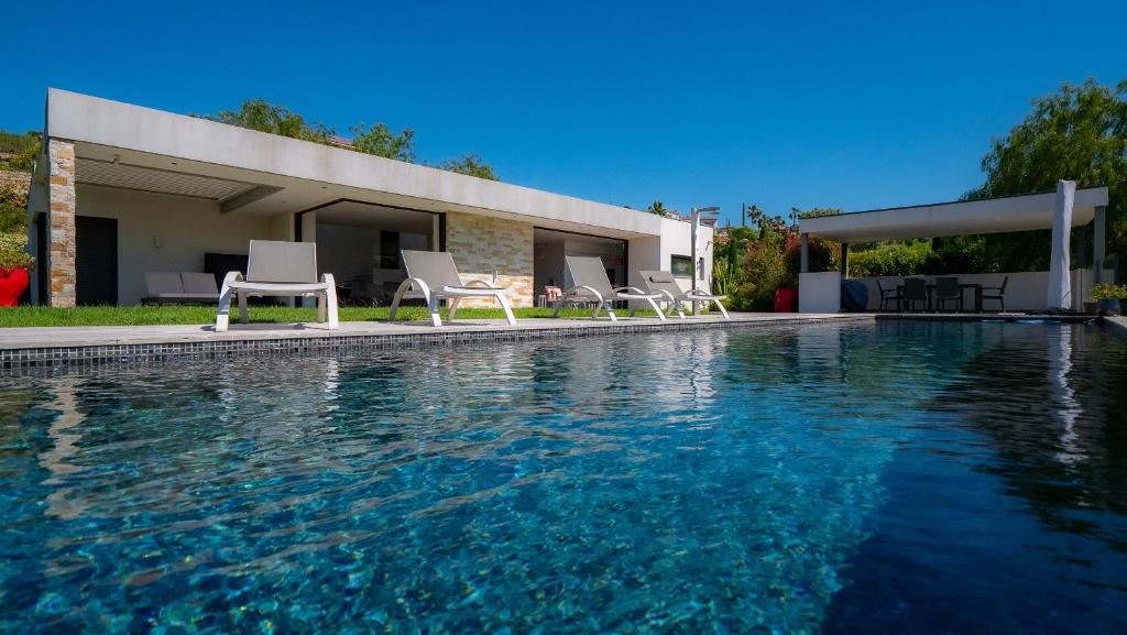 une piscine avec des chaises et une maison dans l'établissement Villa contemporaine classée 5 étoiles avec piscine Antibes, à Antibes