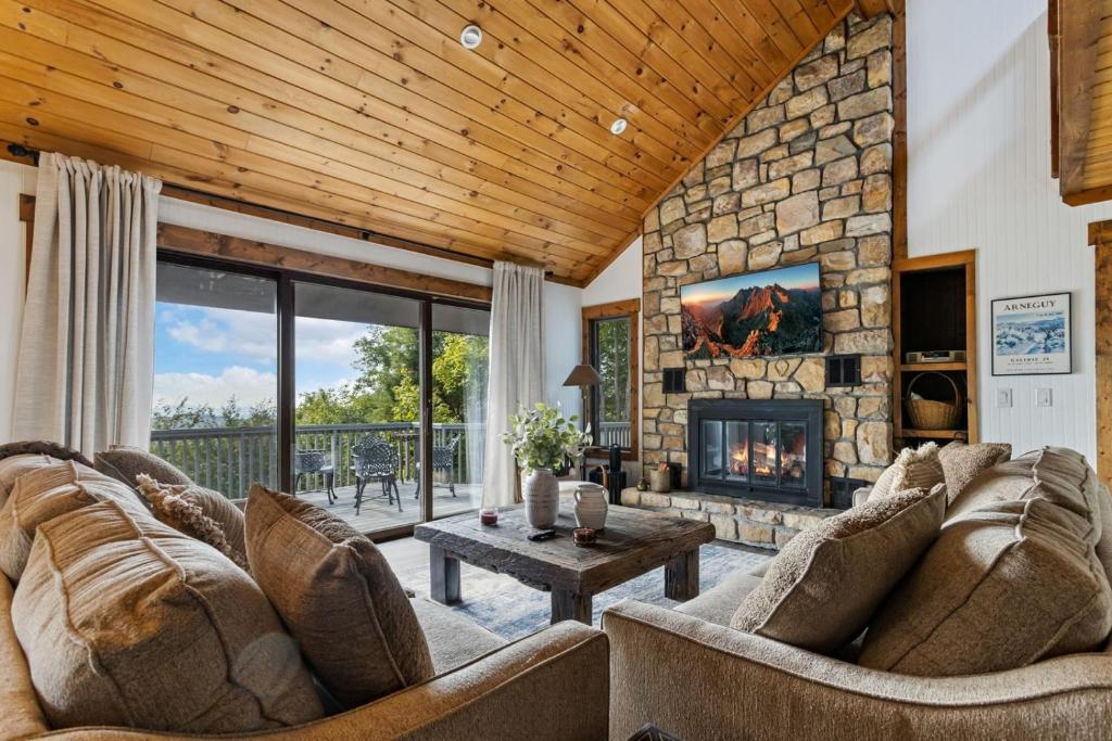 a living room with couches and a stone fireplace at Wishlist in Beech Mountain
