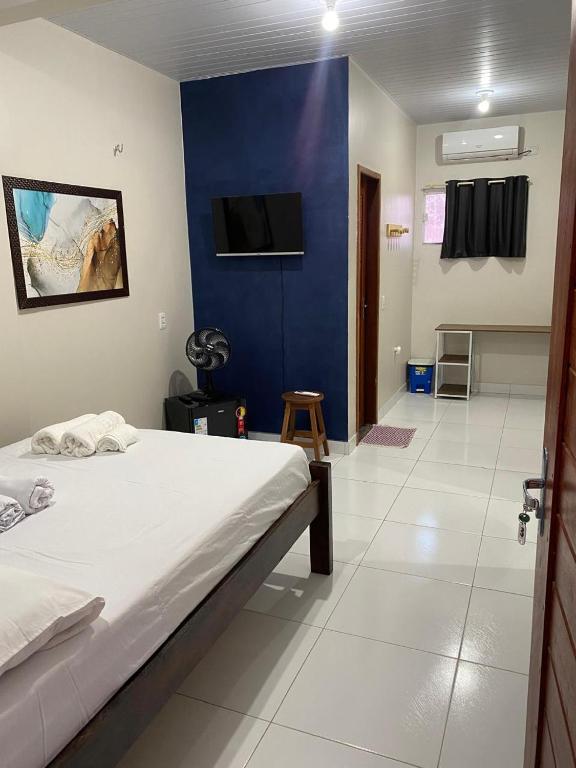 a bedroom with a bed and a blue wall at Temporada BHS Quarto 3 in Barreirinhas
