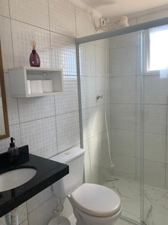a bathroom with a toilet and a glass shower at Riviera Massaguaçu in Massaguassu