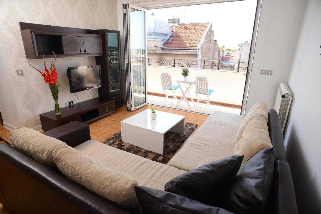 uma sala de estar com um sofá e uma grande janela em Apartments Belvedere em Belgrado