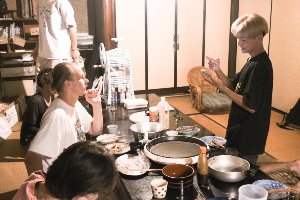 a group of people sitting around a table eating food at Guesthouse SETOUCHI LIFE in Kure