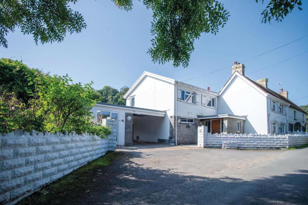 a white house with a white retaining wall at Bryn View – 5 Bedroom Holiday Home – Oxwich in Oxwich