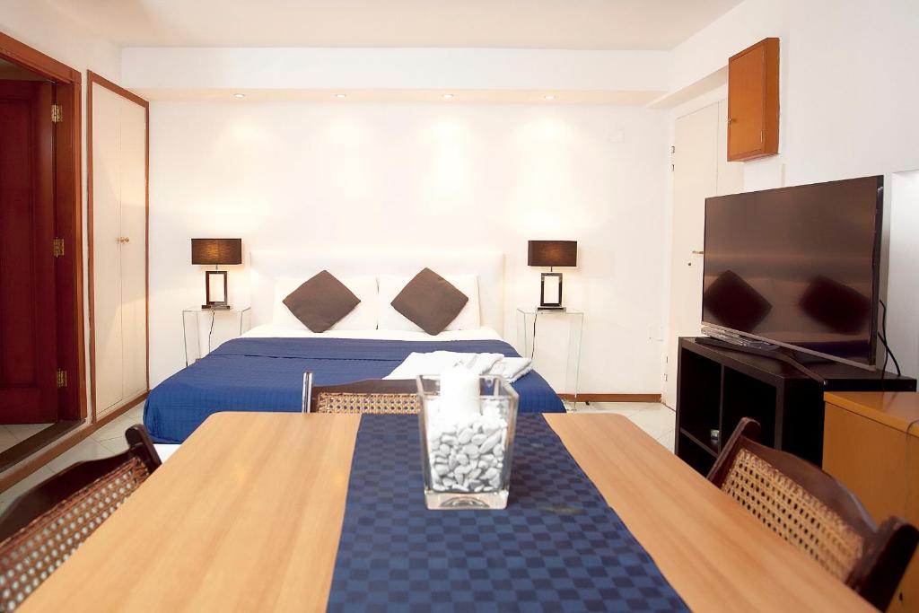 ナポリにあるPlebiscito Apartmentのベッド、テーブル、テレビが備わるホテルルームです。