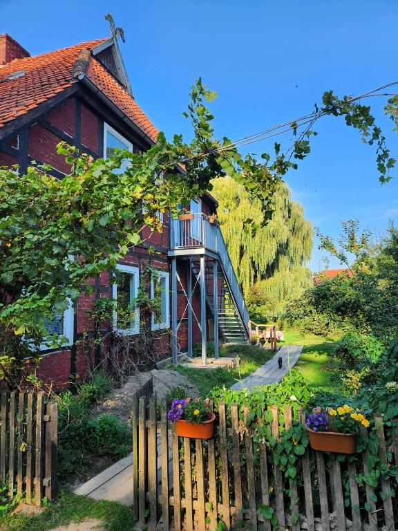 a house with a fence and flowers in front of it at Hof KuMa in Uelzen