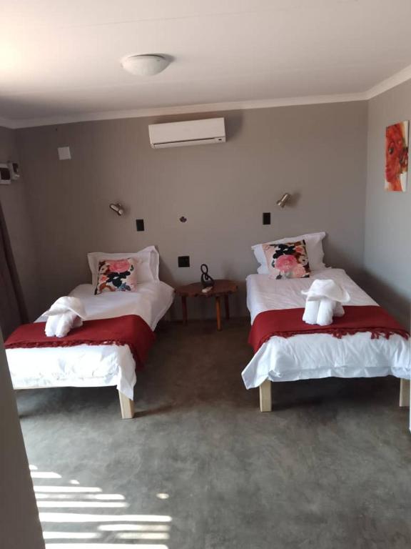 a bedroom with two beds with red and white sheets at Petrified forest restcamp in Khorixas