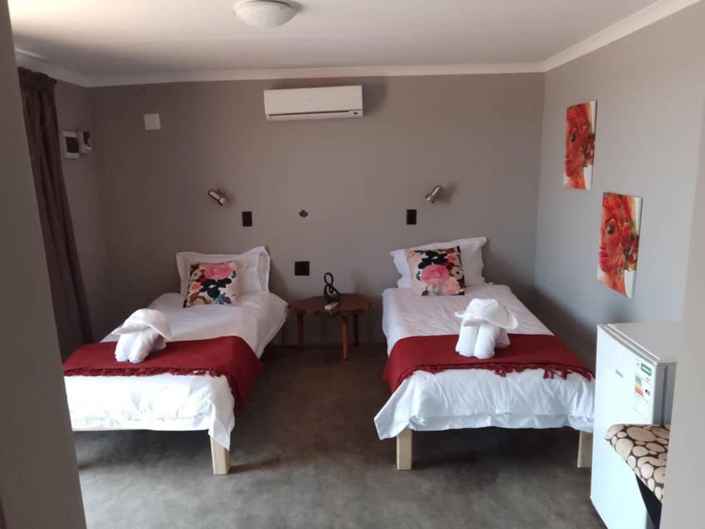 een slaapkamer met twee bedden met rode en witte lakens bij Petrified forest restcamp in Khorixas
