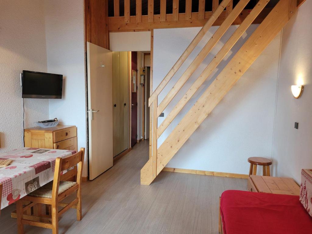 Cette chambre dispose d'un escalier en bois avec une table et des chaises. dans l'établissement Appartement cosy près des pistes avec balcon et TV - FR-1-181-2832, à La Plagne Tarentaise