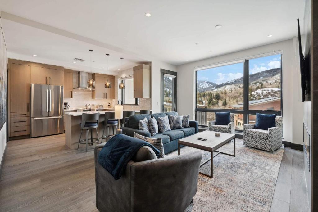 a living room with a couch and a kitchen at One Riverfront Condo 204 by East West Hospitality in Avon