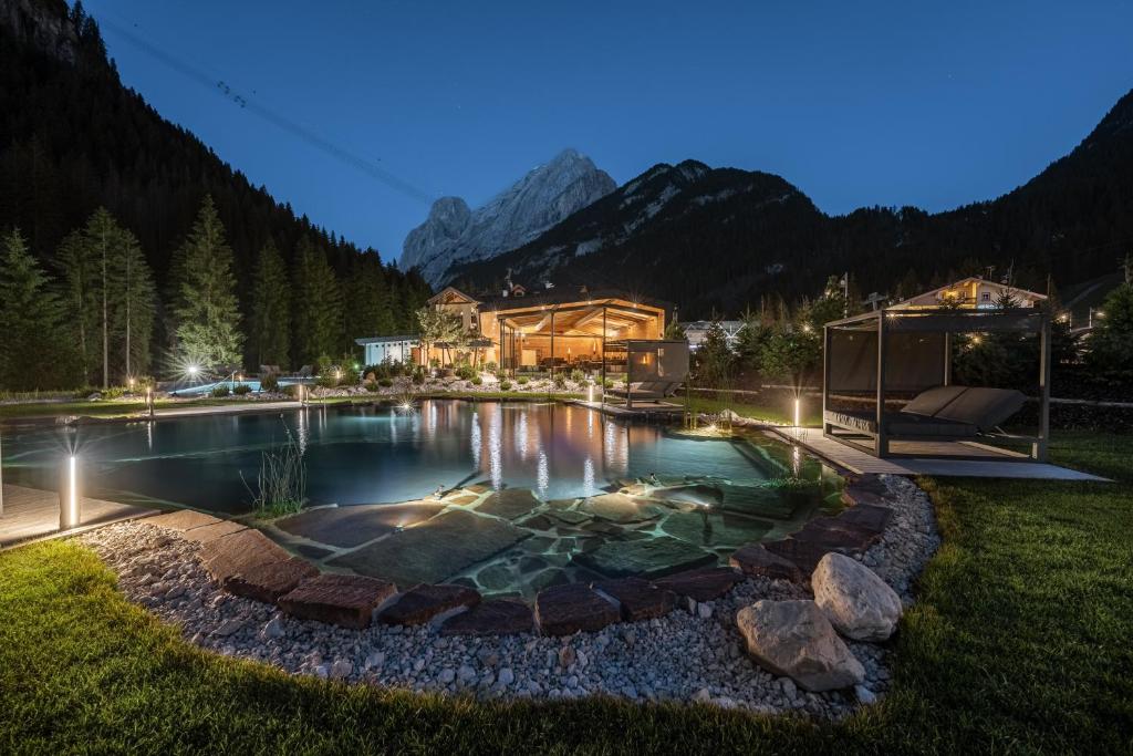 una casa con piscina por la noche con montañas en Hotel Majon Miramonti, en Canazei