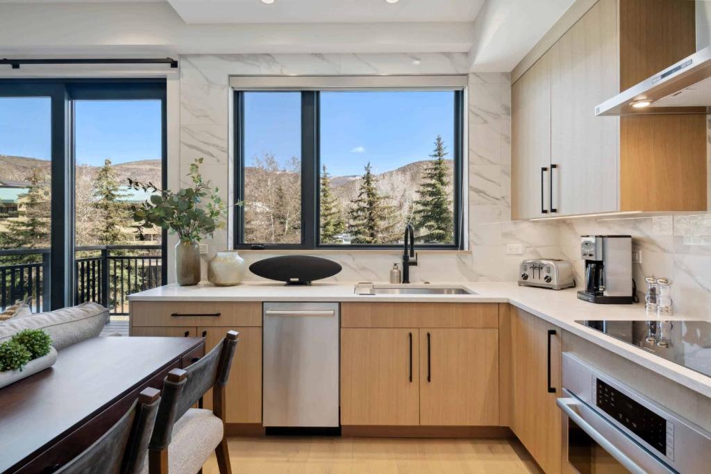 a kitchen with a large window and a table with chairs at One Riverfront Condo 103 by East West Hospitality in Avon