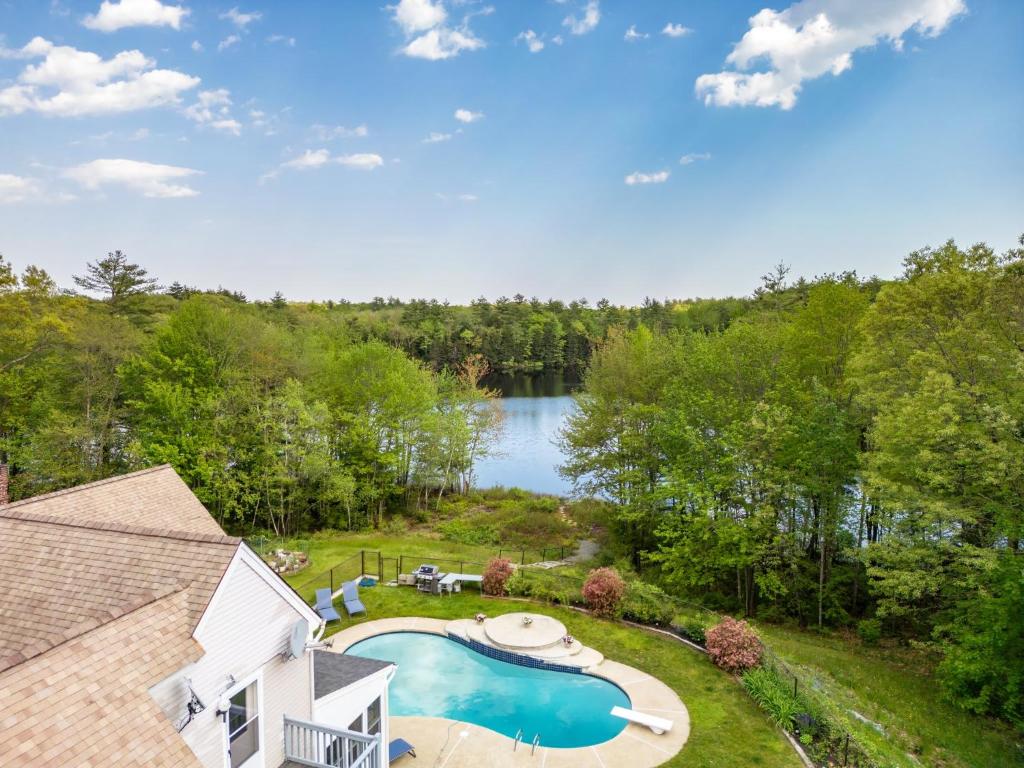 an aerial view of a backyard with a swimming pool and a lake at Maine Pondfront Home Sleeps 22 - Pool & Hot Tub in Sanford