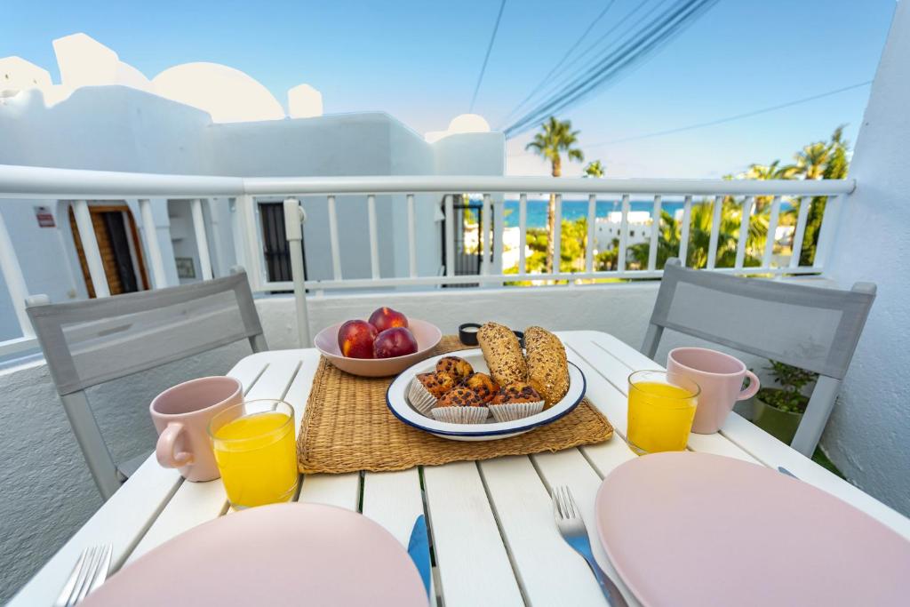 a table with a plate of food and two glasses of orange juice at TrendyHomes Neptuno Mojacar in Mojácar