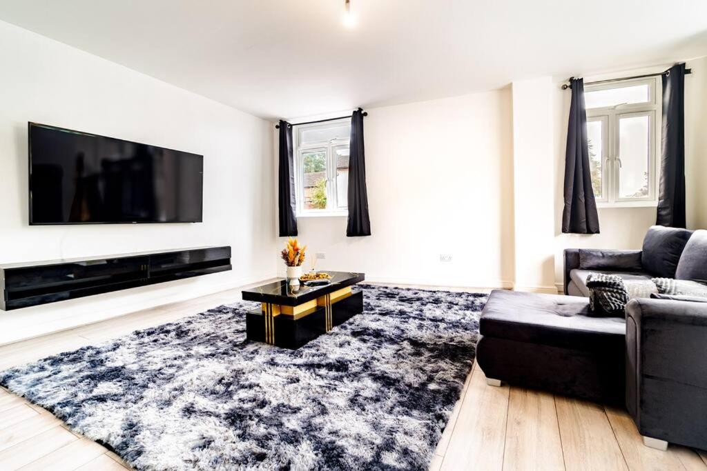 a living room with a couch and a tv at LUX 2BDR Flat By Luton Station, Airport, City Centre - 30min to King's X St Pancras International in Luton