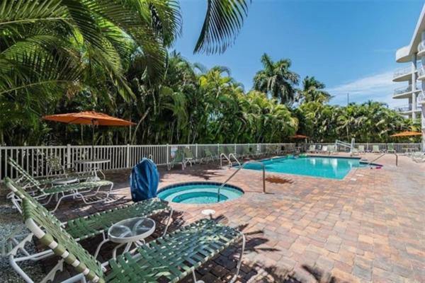a swimming pool with chairs and an umbrella at Coastal Serenity in St Pete Beach