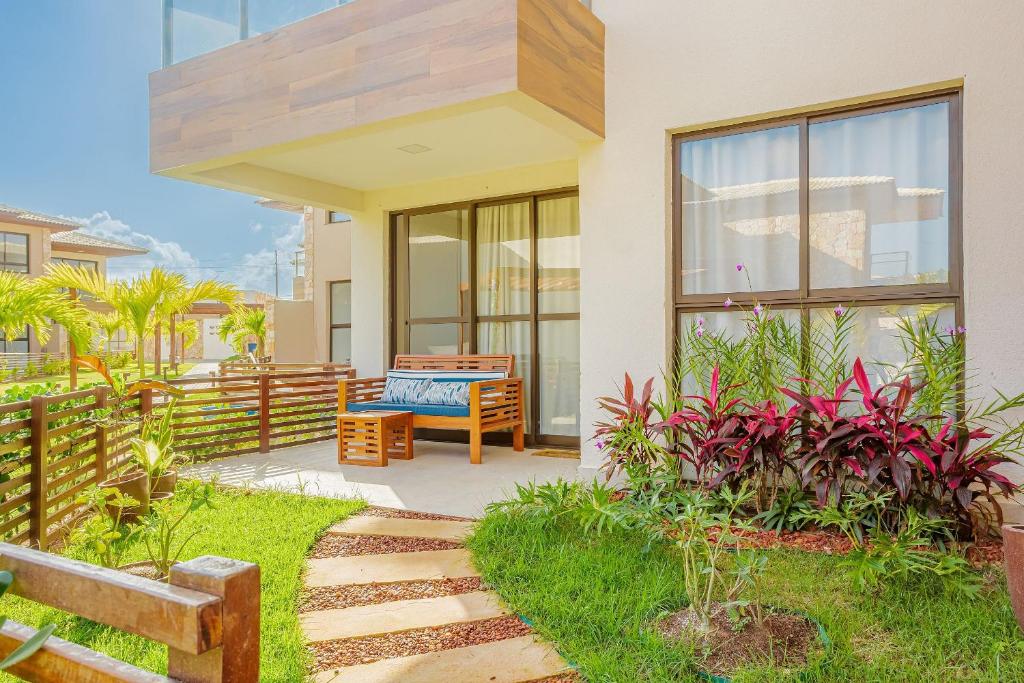 a house with a patio with a bench and plants at GB110 Village Duplex 4 Suítes - Guarajuba in Monte Gordo