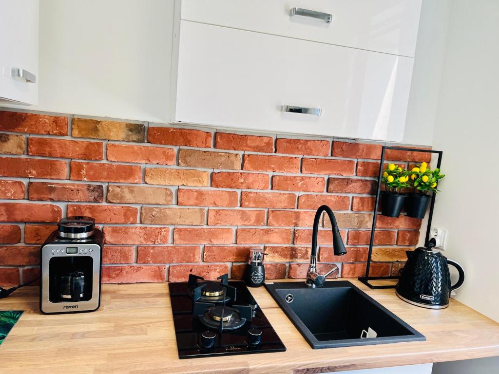 a kitchen counter with a sink and a brick wall at Apartament HAPPY PLACE Family & Business TARGI in Kielce