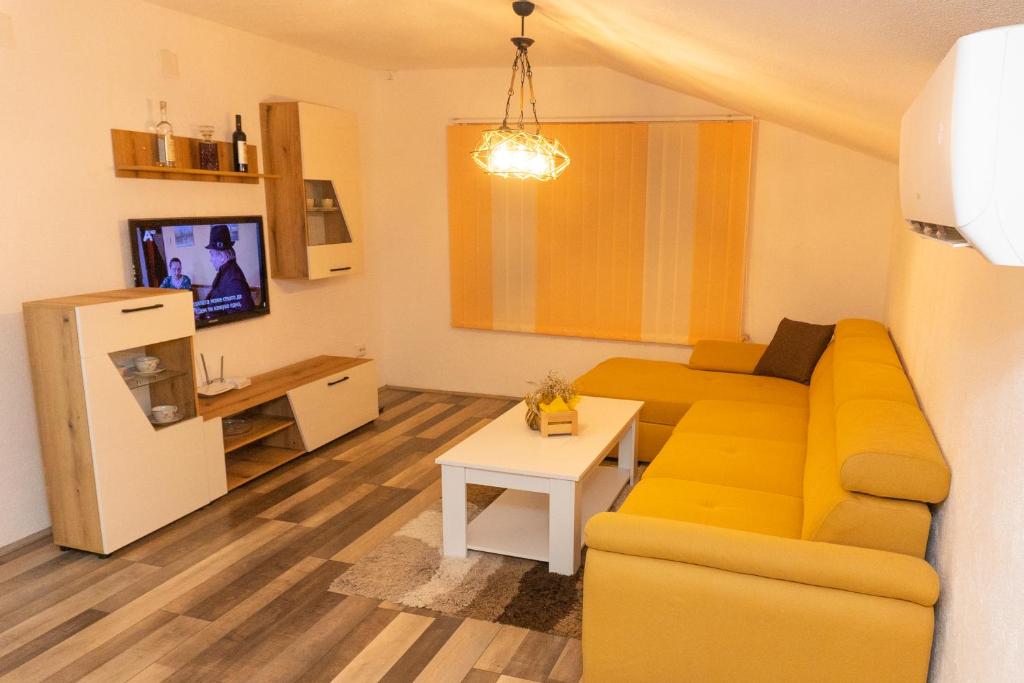 a living room with a yellow couch and a table at Cozy Modern Apartment in Gevgelija