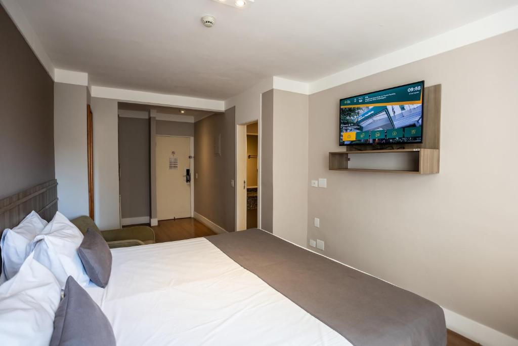 a bedroom with a bed with a television on the wall at Hotel Trianon Paulista in Sao Paulo