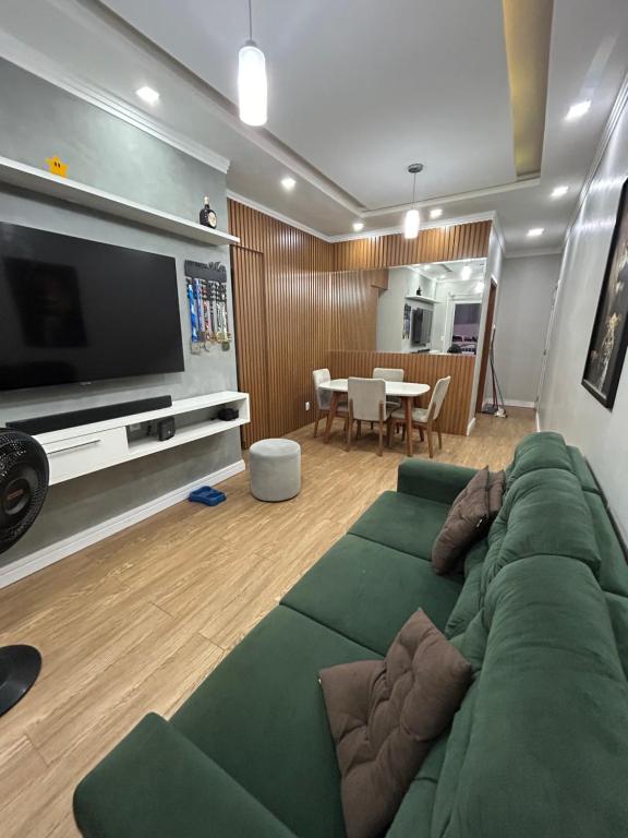 ein Wohnzimmer mit einem grünen Sofa und einem Flachbildfernseher in der Unterkunft Smile Parque das Flores in Manaus