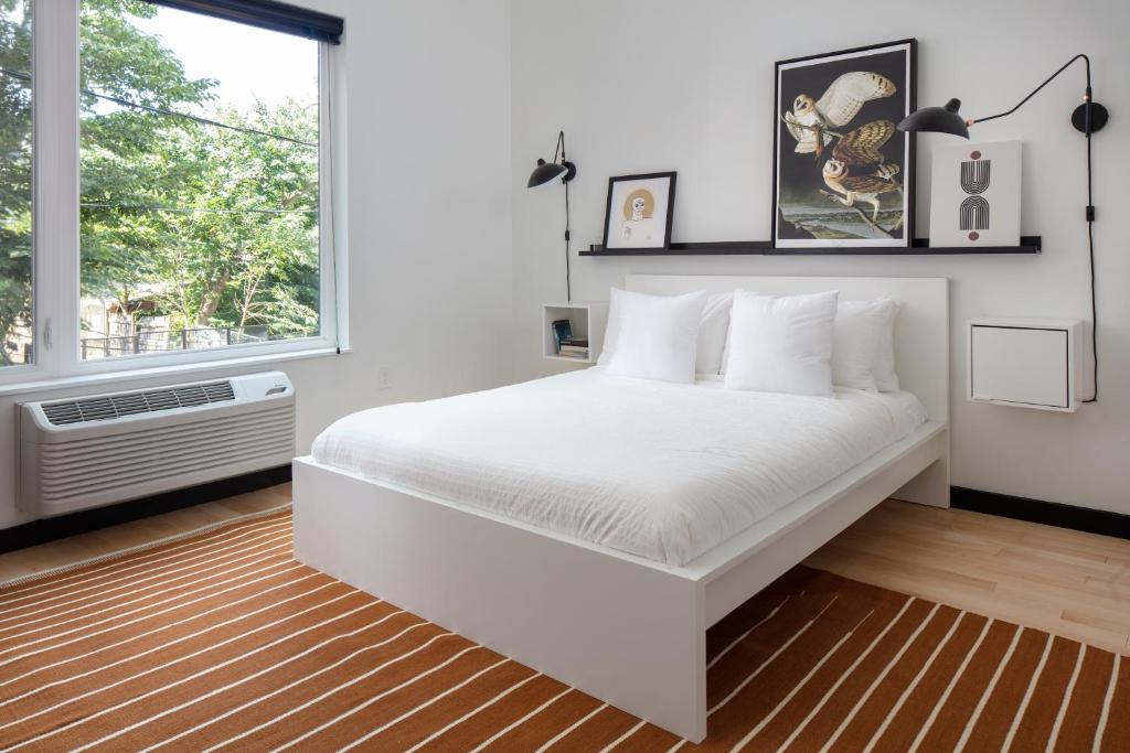 a white bedroom with a large bed and a window at Kasa the Niche University City Philadelphia in Philadelphia
