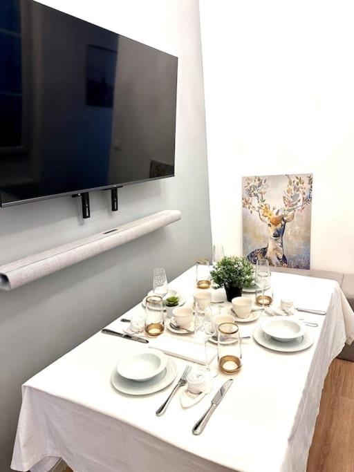 une table blanche avec des assiettes et des verres et une télévision dans l'établissement Appt rénové proche Montmartre Gare du Nord et EST, à Paris