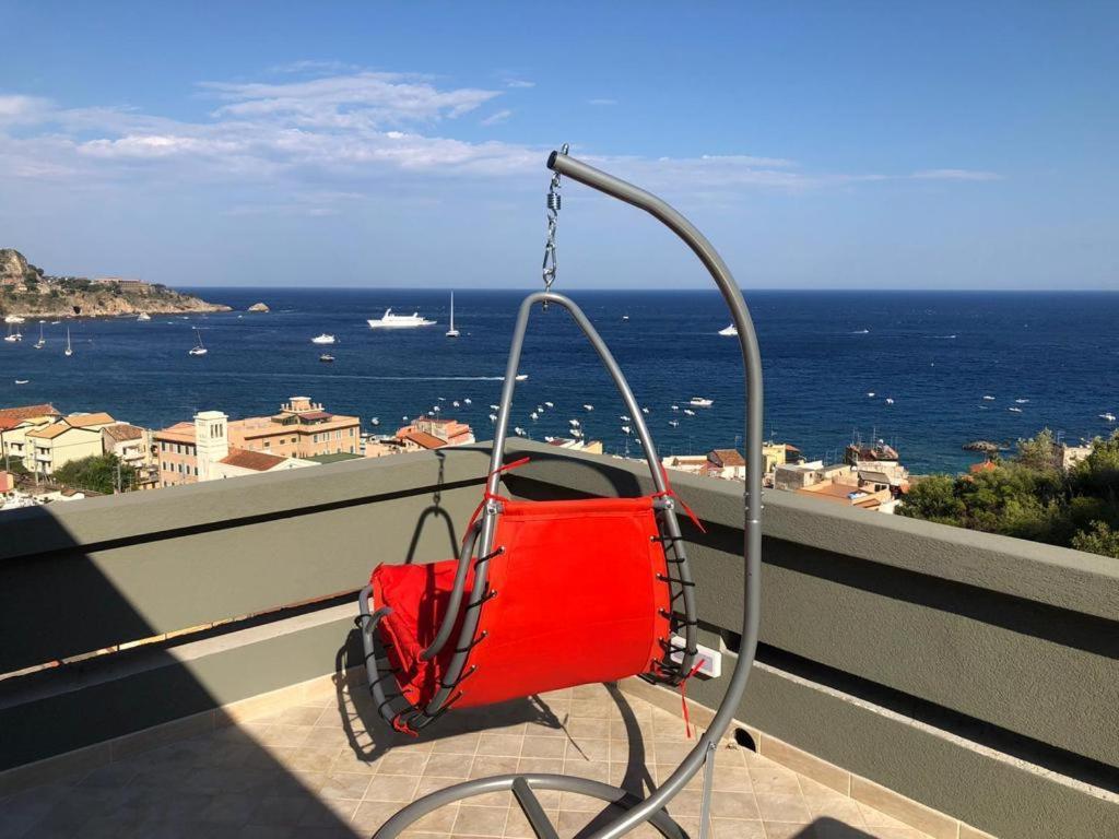 Un columpio rojo en un balcón con vista al océano. en Taormina loview, en Giardini Naxos