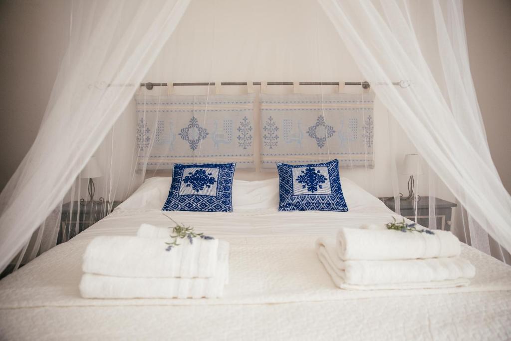 アルゲーロにあるS'Arena Bianca Apartmentの白いベッド(青と白の枕付)
