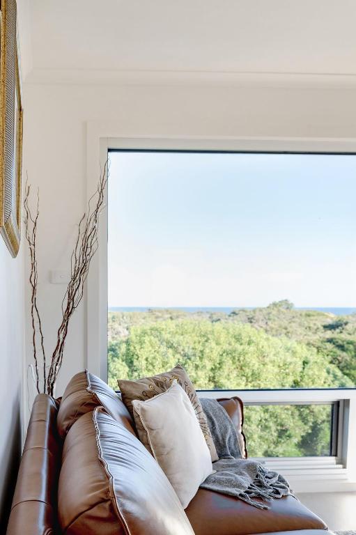a leather couch in front of a large window at Haven Views Harmers Haven in Cape Paterson