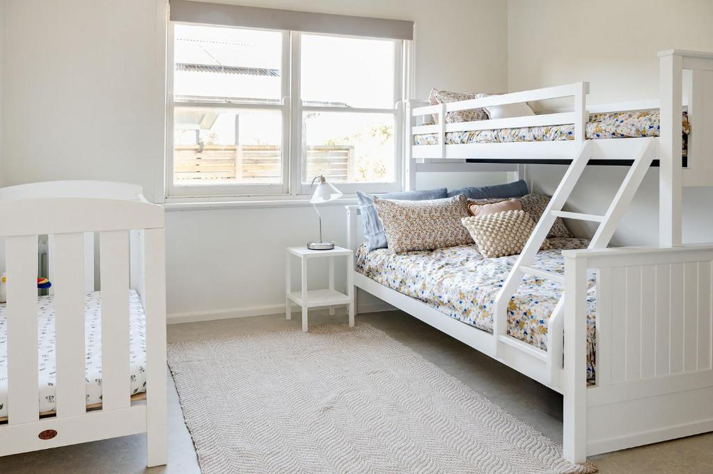 ein Schlafzimmer mit weißen Etagenbetten und einem Fenster in der Unterkunft Haven Views Harmers Haven in Cape Paterson