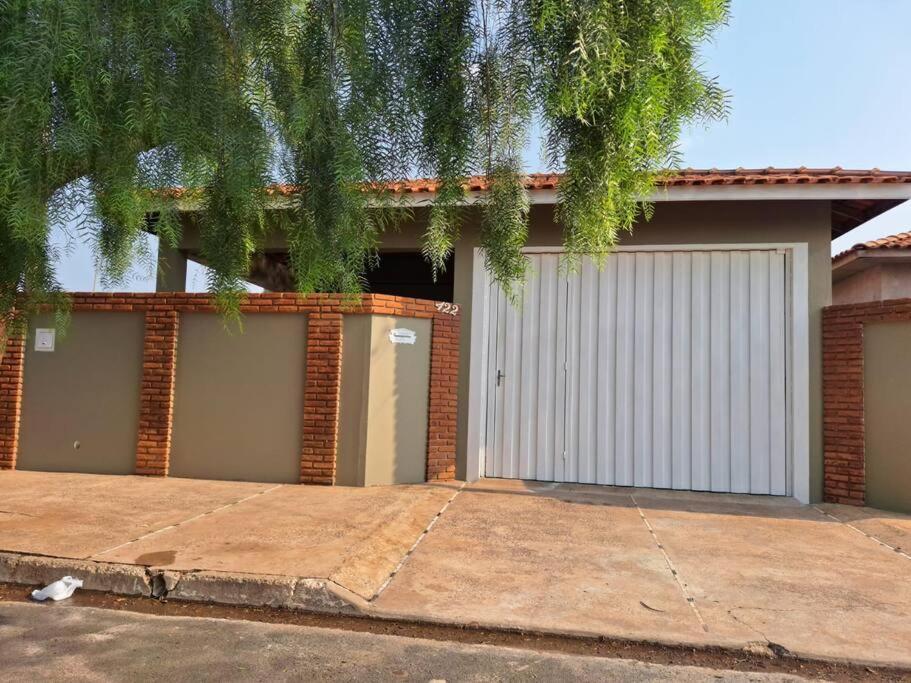 a house with two garage doors and a tree at Casa acolhedora para descanso in Brotas