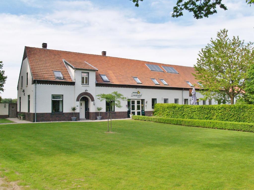 un grand bâtiment blanc avec une cour verdoyante dans l'établissement Hotel Lemmenhof, à Ell