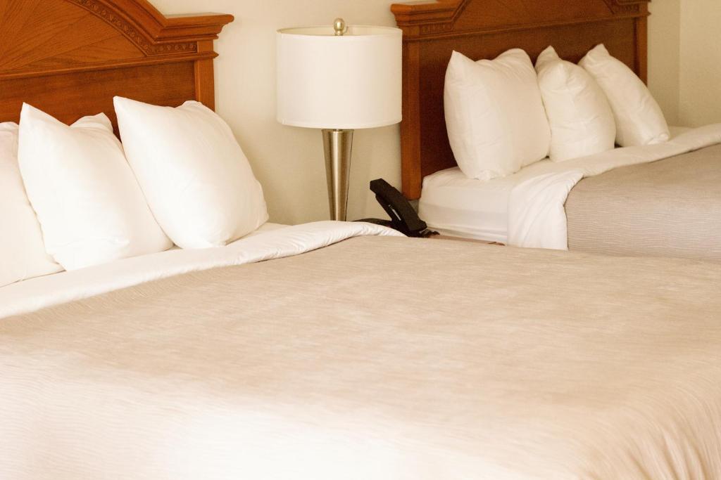 two beds in a hotel room with white pillows at Quality Inn near Chattanooga South in Ringgold