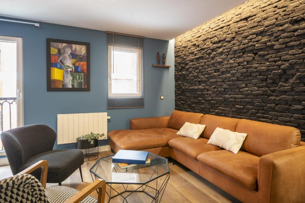 a living room with a couch and a brick wall at Loft Garmendia con PlayStation in Santander