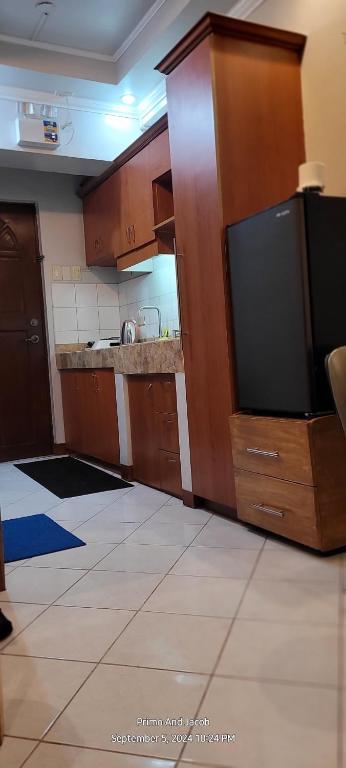 a kitchen with wooden cabinets and a large flat screen tv at COMFY 1-BR Condo near SLEC, US Embassy, Malls,Park in Manila