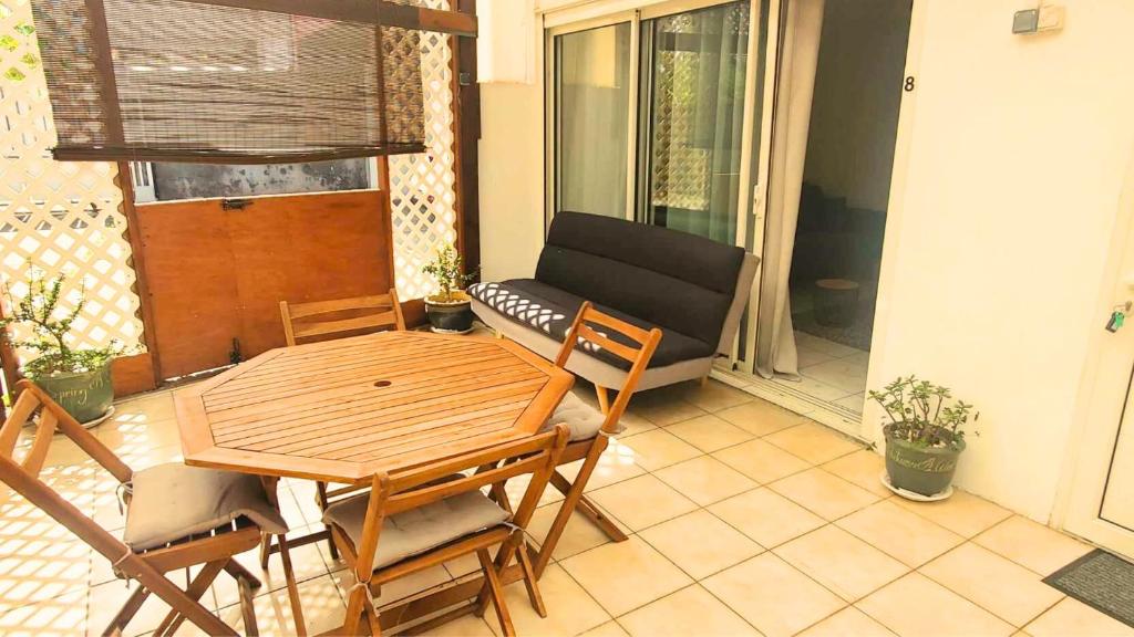 a patio with a table and chairs and a couch at L'Emeraude in Saint-Pierre
