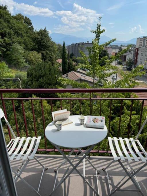 d'une table blanche et de deux chaises sur un balcon. dans l'établissement Appartement calme avec vue à 20 minutes de la gare, à Saint-Égrève