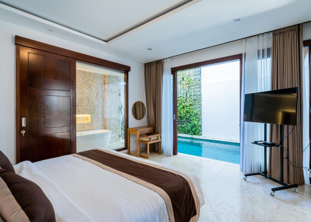 une chambre avec un lit, une baignoire et une télévision dans l'établissement Bali Residence Villa, à Uluwatu