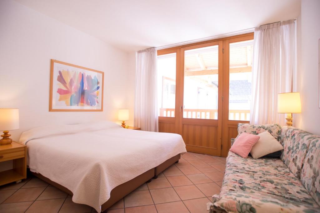 a bedroom with a bed and a couch and a window at America Apartments in Trento